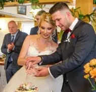 Hochzeitsfotograf fotografiert wie das Paar die Hochzeitstorte anschneidet
