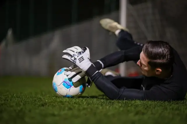 Torwart hält den Ball mit den neuen Torwarthandschuhe, die als Produkt verkauft werden und vom Fotograf fotografiert wurden.